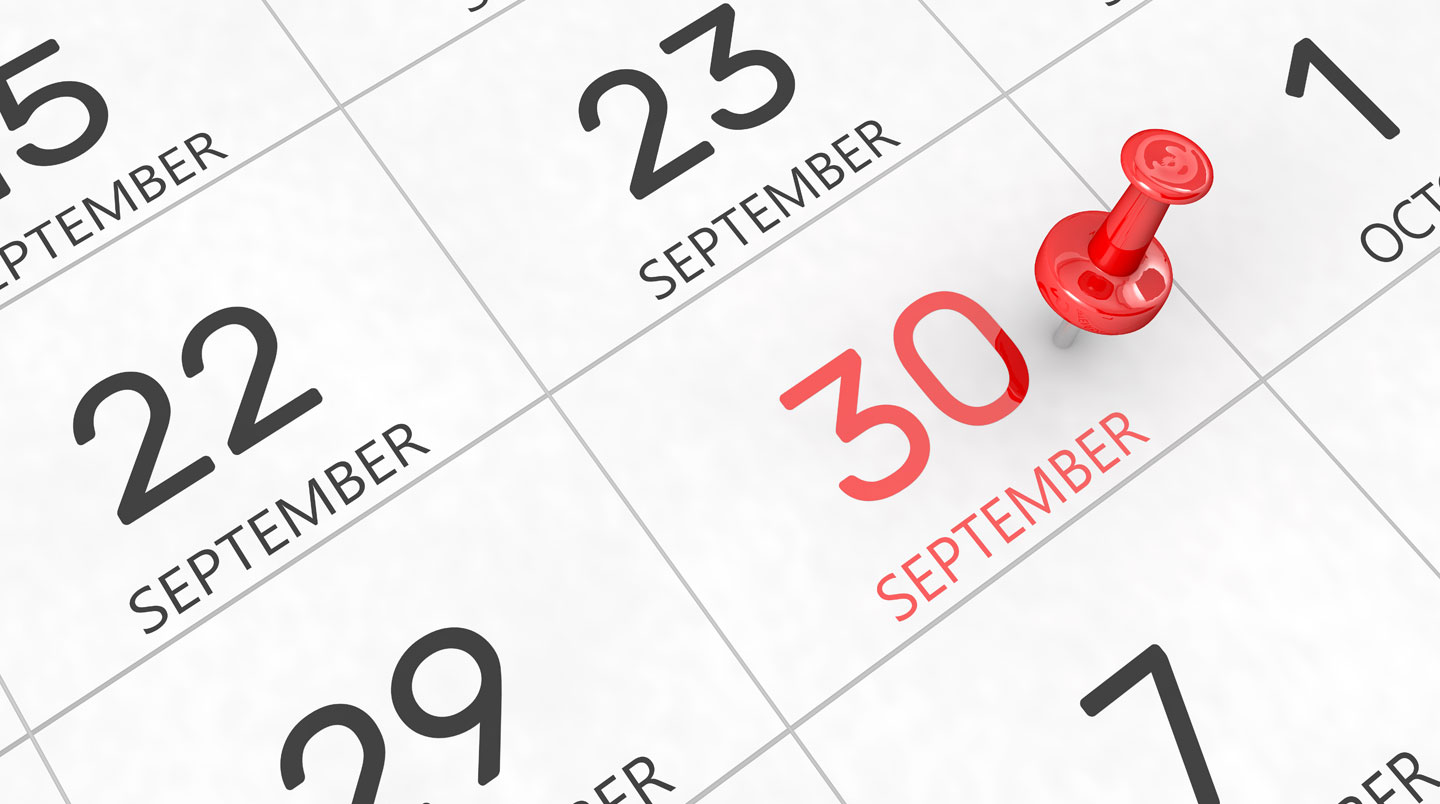 Planning mural de bureau avec les dates septembre 2026 et septembre 2027 marquées et encadrées, personne consultant des documents en arrière-plan